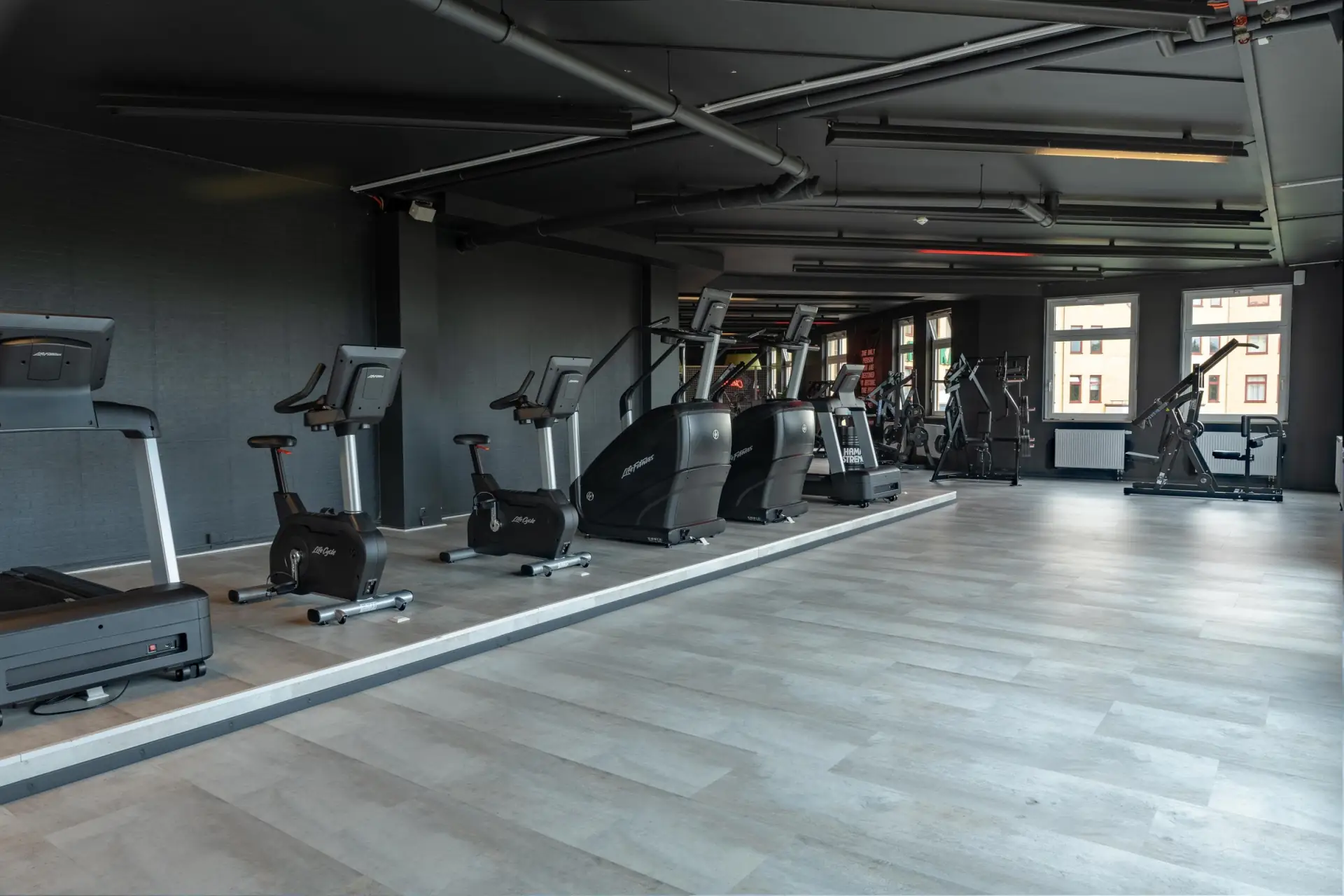 Cardio-Bereich mit Laufband, Fahrrädern und StairMaster an der Fensterfront