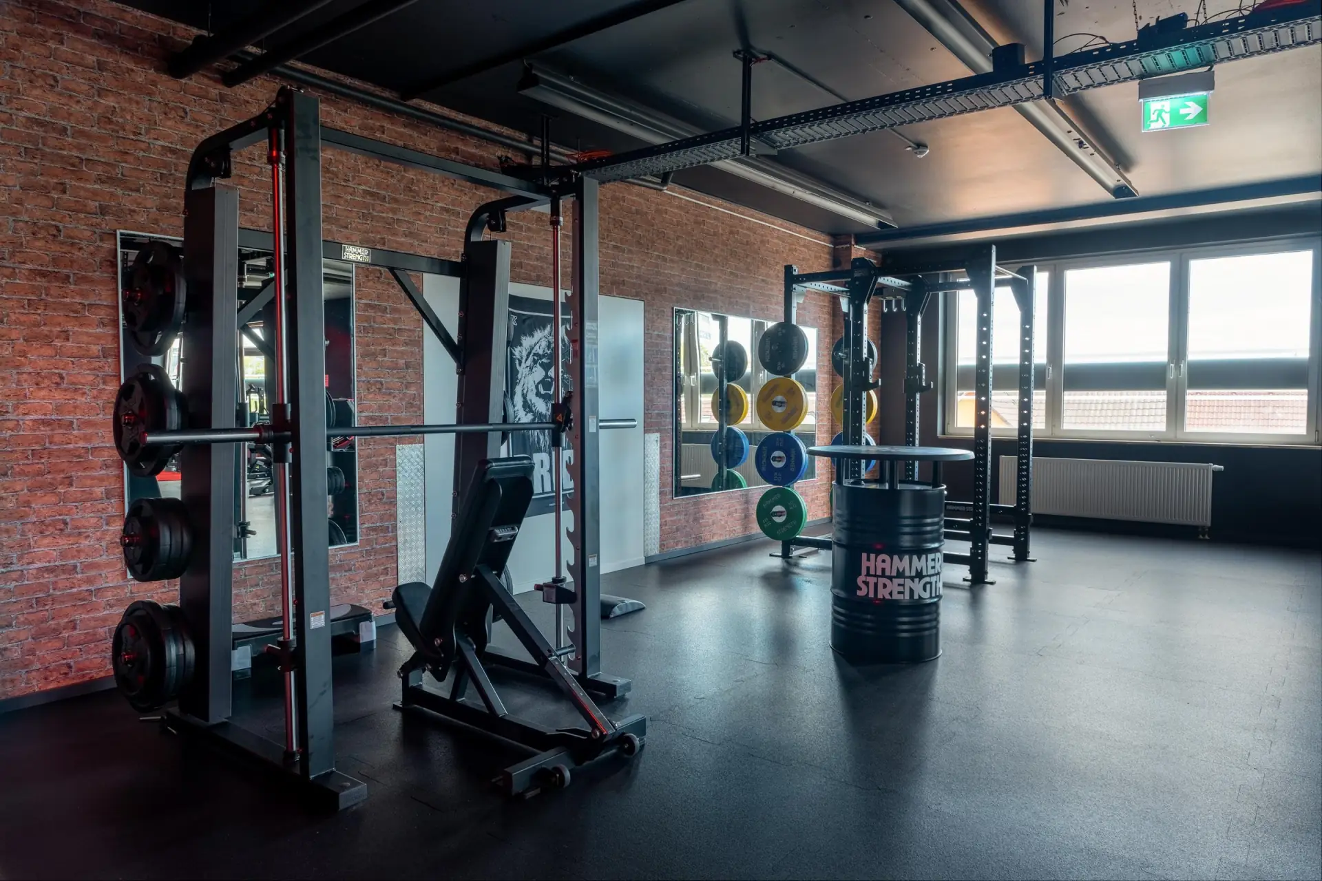 Hammer Strength Rack mit Bumper Plates vor der Backsteinwand